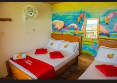 a bedroom with two beds and a painting of flamingos at TESORO de BARU in Cartagena de Indias