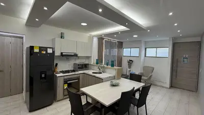a kitchen with a table and a black refrigerator at Apartamentos Crespo 67 aeropuerto in Cartagena de Indias