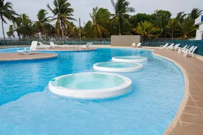 a large swimming pool with white chairs in the water at Hermoso Apartamento Frente al Mar 2 Habitaciones PAZ146 in Coveñitas