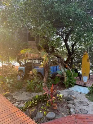 an old car parked in a yard with a surfboard at COCO SALVAJE Tree House in La Rada