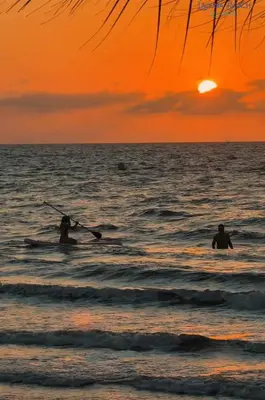 two people in the water at the beach at sunset at Un paraíso frente al mar in San Silvestre