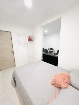 a white bedroom with a bed and a table at Cozy Beachside 3BR Apartment near the Walled City in Cartagena de Indias