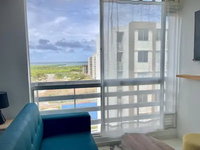 a living room with a blue couch and a large window at Apartamento con vista única cerca de la Uninorte in Puerto Colombia