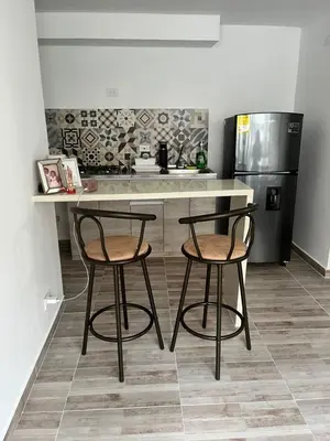 a kitchen with two stools and a counter with a refrigerator at Margarita's apartment in Puerto Colombia