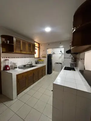 a large kitchen with wooden cabinets and white tile floors at Hostal Tayrona in Santa Marta