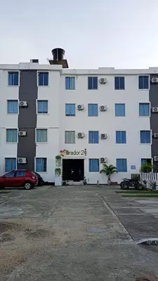 a large white building with a car parked in a parking lot at Apartamento con piscina in San Silvestre