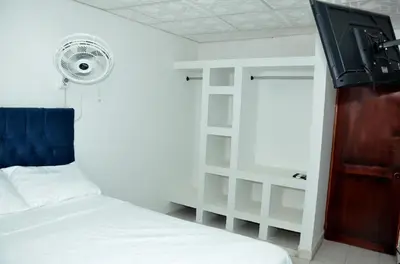a bedroom with a white bed and a fan at La Armonia in Cartagena de Indias