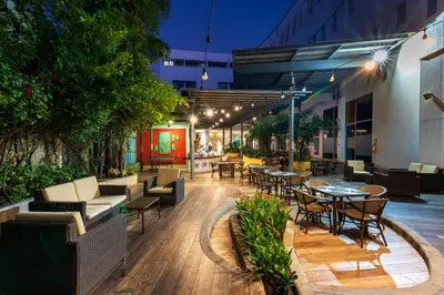 an outdoor patio with tables and chairs and trees at Pop Art Hotel CLC Puerto Mamonal Cartagena in Cartagena de Indias
