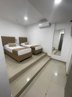 a bedroom with two beds and a mirror in it at HS-T Habitacion Triple con wifi, piscina y aire acondicionado in Cartagena de Indias