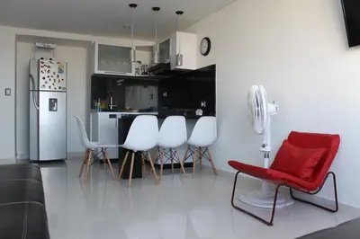 a kitchen with a red chair and white chairs at Arriendos S.H. Nuevo Conquistador in Cartagena de Indias