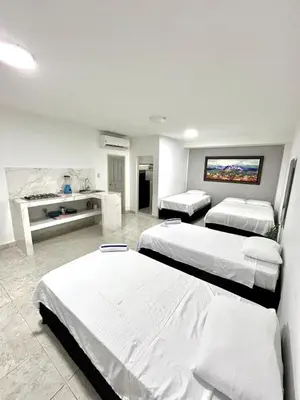 a hotel room with three beds and a desk at Comfortable loft in Barranquilla in Barranquilla