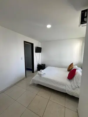 a bedroom with a bed with white sheets and red pillows at Portofino Apartments in Cartagena de Indias