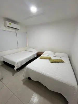 two beds in a room with white walls at Portofino Apartments in Cartagena de Indias