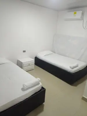 two beds in a room with white walls at 5 minutos del Castillo san Felipe in Cartagena de Indias