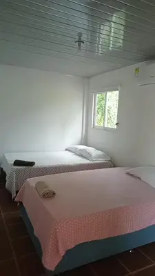 two beds in a white room with a window at Dulce Barú in Cartagena de Indias