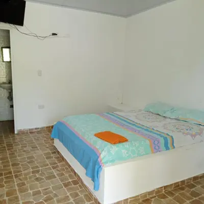 a white bed with an orange shirt on it at Dulce Barú in Ararca