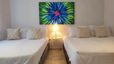 two beds in a room with a painting on the wall at Spectacular Villa Near Walled City in Cartagena de Indias