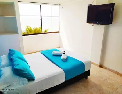 a bedroom with a bed with blue pillows and a television at comodo apto marbella b17 in Cartagena de Indias