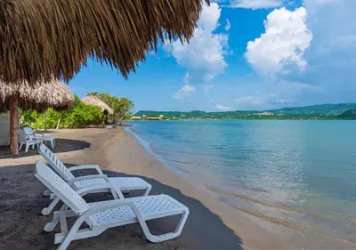 two white chairs on a beach next to the water at Marina Puerto Velero, Villa frente al Mar in El Morro