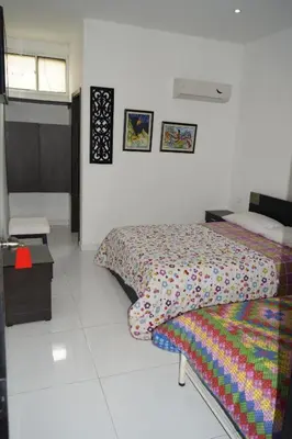 a bedroom with two beds and a table and avertisement at Hotel Mar di Plata in Barranquilla