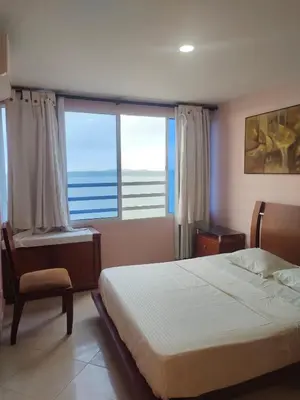 a bedroom with a bed and a chair and a large window at Apartaestudio en el Laguito in Cartagena de Indias