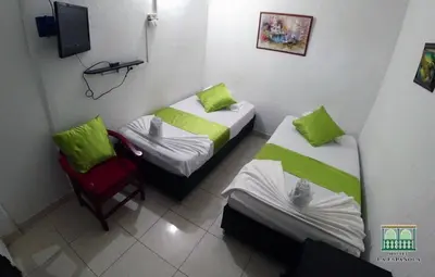 two beds and a chair in a room at Hostal La Española de Getsemani in Cartagena de Indias