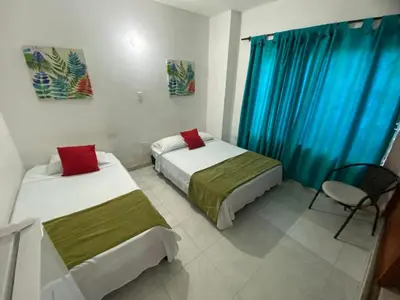 two beds in a room with blue curtains at Paraíso en Bocagrande habitaciones in Cartagena de Indias
