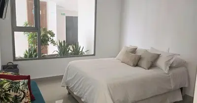 a bedroom with a white bed with two windows at Altamar vista al mar in Cartagena de Indias