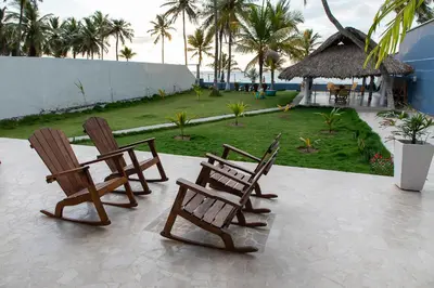 three wooden chairs sitting on a patio with a yard at Cabaña Tio Chin in Coveñas
