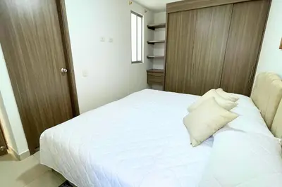 a bedroom with a white bed and a wooden cabinet at Apartmento En Miramar in Barranquilla
