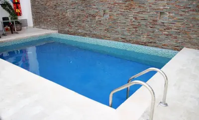 a swimming pool with two chairs next to a brick wall at Hotel Continental Plaza Barranquilla in Barranquilla