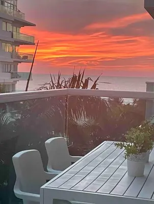 a table and chairs on a balcony with a sunset at Apartamento para viajar en familia in Cartagena de Indias