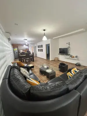 a living room with a black leather couch at Casa de campo con piscina, aire acondicionado, estacionamiento privado con BBQ in Barranquilla