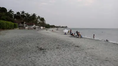 a group of people on a beach near the water at Jardín de Díos in Santa Marta