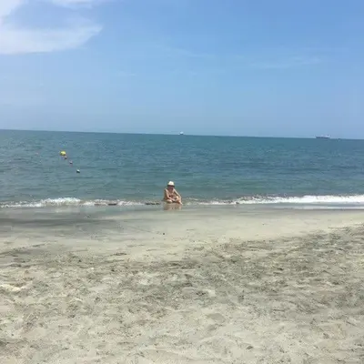 a man sitting on the beach near the ocean at Jardín de Díos in Santa Marta