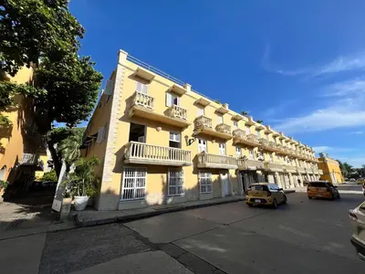 a yellow building with balconies and a car parked in front at Apartamento en ciudad amurallada centro histórico Cartagena de Indias, Colombia in Cartagena de Indias