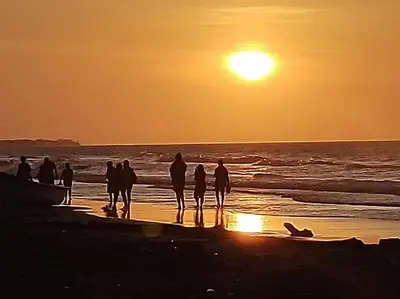 a group of people standing on the beach at sunset at la casablanca moñitos in Moñitos