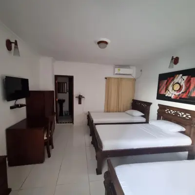 a room with three beds and a flat screen tv at Hotel Cartagena Comfort in Cartagena de Indias