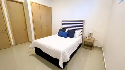 a white bedroom with a bed with blue pillows at Magico Apartamento Frente al Mar 4 Habitaciones BM83 in Coveñas