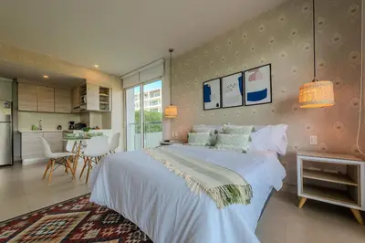 a bedroom with a large white bed and a kitchen at Condominio frente al mar con acceso directo a la playa Morros IO in Cartagena de Indias