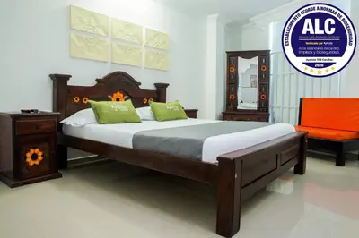 a bedroom with a bed and a orange chair at Ayenda 1315 Candiac in Barranquilla