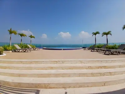 a group of benches and a pool with palm trees at Lujoso Penthouse Duplex 403m2 con Terraza Privada y vista al mar in Cartagena de Indias