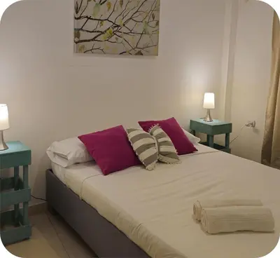 a bedroom with a bed with pillows and two tables at Apartamentos Santori in Cartagena de Indias
