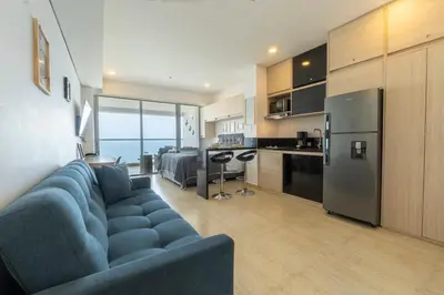 a living room with a blue couch and a kitchen at Sunset Oceanfront Studio in Cartagena de Indias
