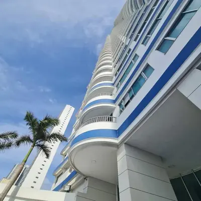 a tall building with a palm tree next to it at Oceanfront apartment in Cartagena in Cartagena de Indias
