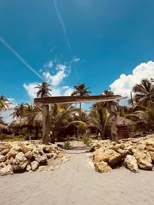 a wooden arch on a beach with palm trees and rocks at Casa Origen Boutique en San Bernardo del Viento in San Bernardo del Viento
