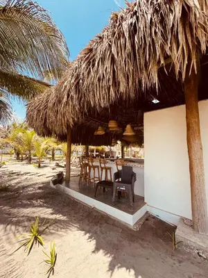 a table and chairs under a straw hut on the beach at Casa Origen Boutique en San Bernardo del Viento in San Bernardo del Viento