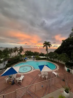 a swimming pool with umbrellas and chairs and the ocean at Unwind in Santa Martas Oceanfront Retreat in Playa Dormida