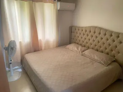 a bed in a bedroom with a fan next to a window at Habitación en Villa Carolina con aire in Barranquilla