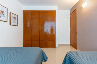 a bedroom with two beds and a wooden closet at Altamar, disfruta la mejor vista in Cartagena de Indias